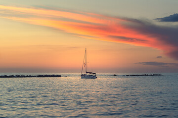 red sunset clouds over a sailing boat at the sea in Anzio, Rome, Italy

