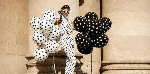 Spring, summer fashion. Glamour, stylish elegant woman in polka dot jumpsuit is holding balloons...