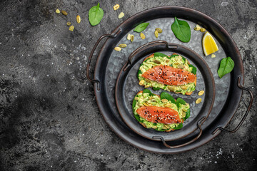 Two toasts whole grain bread with avocado paste and salmon. keto paleo diet. Delicious breakfast or snack. Restaurant menu, dieting, cookbook recipe top view
