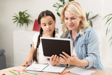 Mother and daughter using digital tablet at home