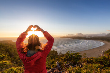 Adventurous Woman Hiker making heart shape with hands at Sandy Beach on the West Coast of Pacific...