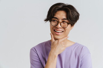 Young handsome smiling asian boy in glasses touching his chin