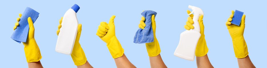 hand with yellow rubber glove holding cleaning supplies on blue background. banner - Powered by Adobe
