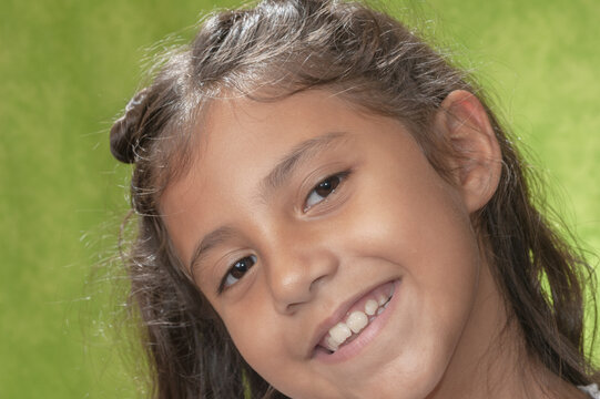 Retrato de niña de ocho años con cabellos largo castaño, feliz, sonriente y haciendo gestos