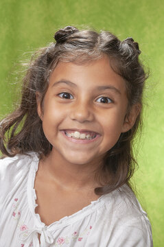 Retrato de niña de ocho años con cabellos largo castaño, feliz, sonriente y haciendo gestos