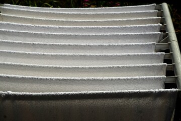 Wäscheständer mit weißen Handtüchern auf Terrasse im Garten am Morgen bei Sonne im Sommer