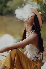 Young woman smokes wei in nature in a hippie way taking a break from the city