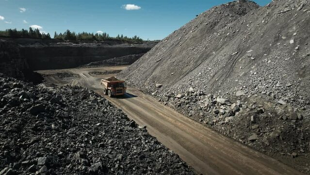 Dump truck working at mining site. Loaded with precious minerals in an open pit. Aerial industrial quarry scene. Pollution, environment and ecology concept