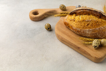 Freshly baked wheat loaf bread on a wooden board on a light background