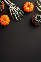 Top view photo of halloween decorations skeleton hands and pumpkins on isolated black background...