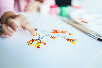 A child draws leafs on a tree. Ideas for drawing with finger paints. Finger painting for kids on white background. Little girl painting by finger hand paint color. Children development concept.