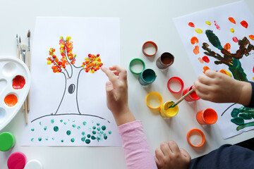 Children draw trees with leaves with colorful paints. Creative activities