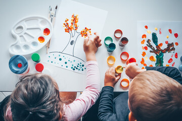 Children draw trees with leaves with colorful paints. Creative activities
