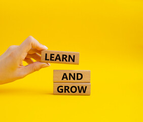 Learn and grow symbol. Concept words Learn and grow on wooden blocks. Beautiful yellow background. Businessman hand. Business and Learn and grow concept. Copy space.