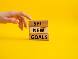 Set New Goals symbol. Wooden blocks with words Set New Goals. Beautiful yellow background. Businessman hand. Business and Set New Goals concept. Copy space.