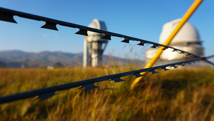 A large observatory is protected by a barbed fence. There is a long sharp wire around perimeter....
