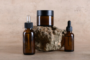 Group of amber glass bottle and jar mockup for moisturizer cream, serum, essensial on stone podium...