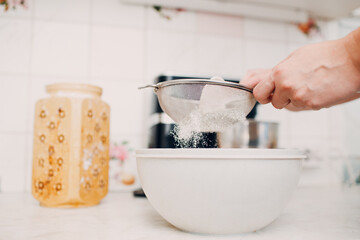 Pastry chef sift pours flour makes cake. Cooking and preparing dessert.