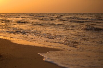 The sandy shore of the Sea of Azov at sunset, a warm summer evening, the waves are beating against...