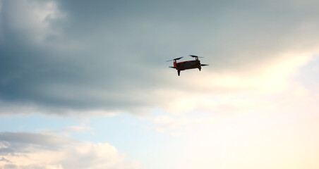 Hovering drone flying upward on a cloudy sky backdrop. copter flying .