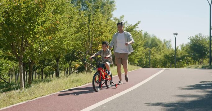 Father teaching son to ride bike,4K
