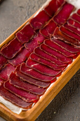 Dried sliced basturma on the Board on brown table