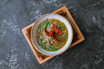soup with chorizo meat and beans on bowl on dark stone table top view