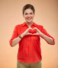 Isolated portrait of smiling  woman in red doing heart simbol on chest.
