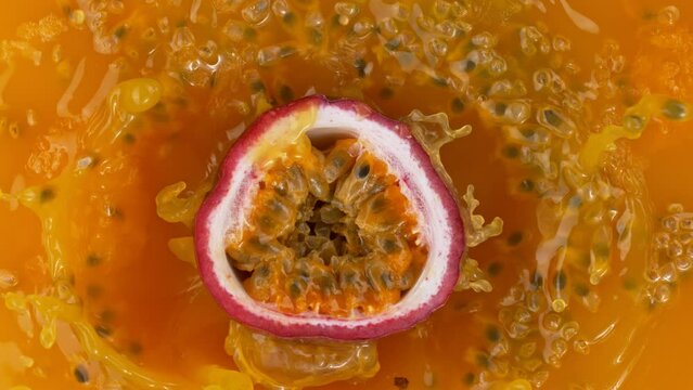 Fresh sliced passion fruit falling into juice, super slow motion filmed on high speed cinematic camera at 1000 fps.