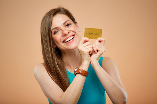 Smiling woman with credit card isolated portrait on yellow brown background.