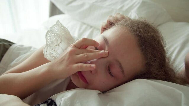 Portrait cute upset little girl with big tears flowing down his cheeks, the child lies at home on bed next to his mother and cries, tears flow with an upset face. Mom takes pity on her daughter.