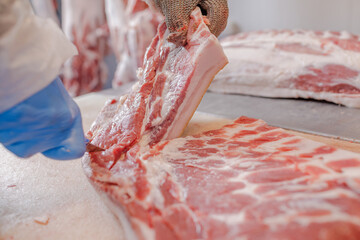 close-up of meat processing in the food industry, a worker cuts raw pork, the concept of meat...