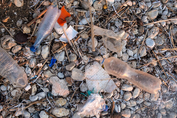 Plastic garbage on the seashore. Top view of a polluted beach. Stones and shells mixed with plastic. Environment concept