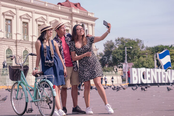 Obraz premium Happy tourists taking selfies with smartphones in a park in downtown El Salvador. Hispanic people.