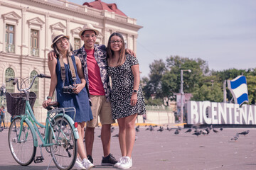 Portrait of young Hispanic tourists with bicycles in the central park in  El Salvador. - obrazy, fototapety, plakaty