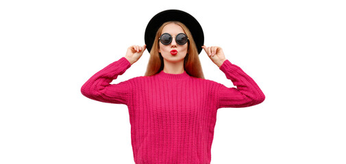 Portrait of beautiful young woman model blowing her red lips wearing pink knitted sweater and black round hat isolated on white background