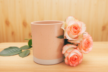Pink cup of tea or coffee with rose flowers - vintage card with wooden background