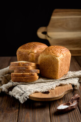Fototapeta na wymiar loaves and sliced ​​pieces of cornbread on a wooden board, dark background