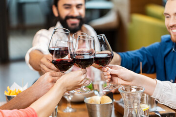 leisure, people and celebration concept - close up of happy friends drinking red wine and toasting at restaurant or pub