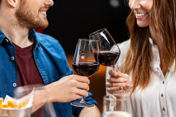 leisure, drinks and people concept - close up of happy couple drinking red wine at restaurant