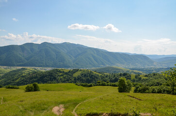 Fototapeta na wymiar Summer mountain landscape with green rolling hills and the village in the valley in to the distance. Kolochava Transcarpathia, Carpathian Mountains, Ukraine 