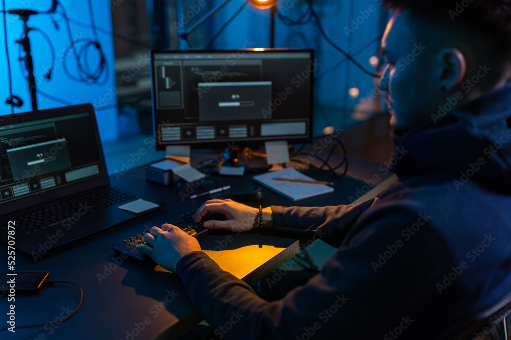 Poster cybercrime, hacking and technology concept - close up of male hacker in dark room writing code or us