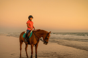 15 year old rider standing on the shore riding her horse