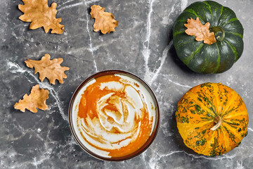 Obraz na płótnie Canvas Pumpkin cream soup with cream and organic decorative pumpkins