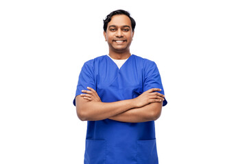 healthcare, profession and medicine concept - happy smiling indian doctor or male nurse in blue uniform with crossed arms over white background