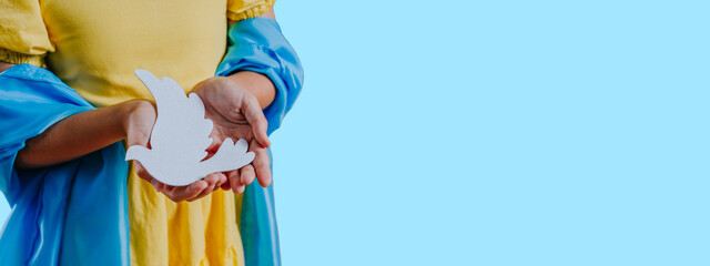 Close up of girl with Ukrainian flag holding white paper pigeon