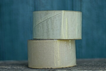 two large rolls of transparent tape lie on a gray table against a green background