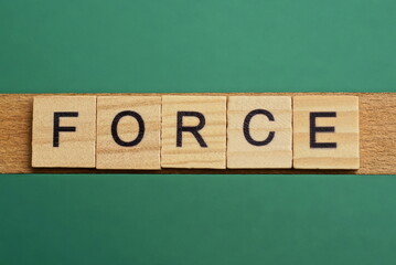 gray word force from small wooden letters on a green table