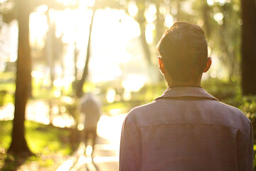 hopeful young man looking at the sunset in profile and turning his back smiling and contemplating the sun.