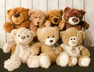 A family of teddy bears sit together in a friendly company on a wooden background.  Children's joy soft toys.  Photo front close-up, front view.